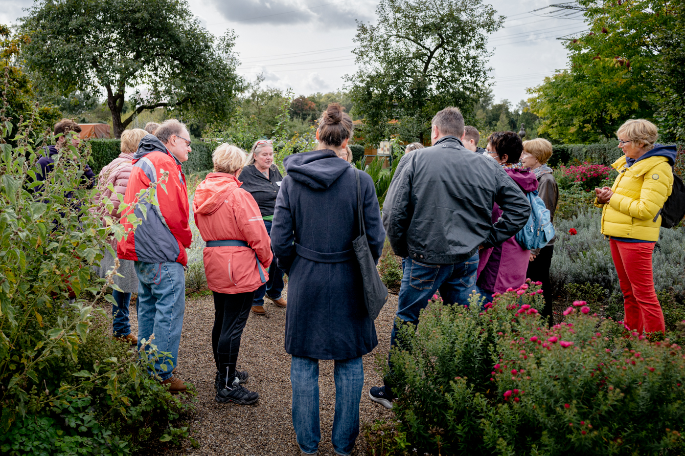 Zur Veranstaltung NaturGartentag 2024, das Foto zeigt eine Gruppe Menschen versammelt in einem blühenden Garten